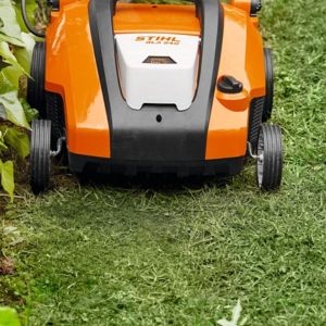 an orange cordless scarifier on the edge of a lawn