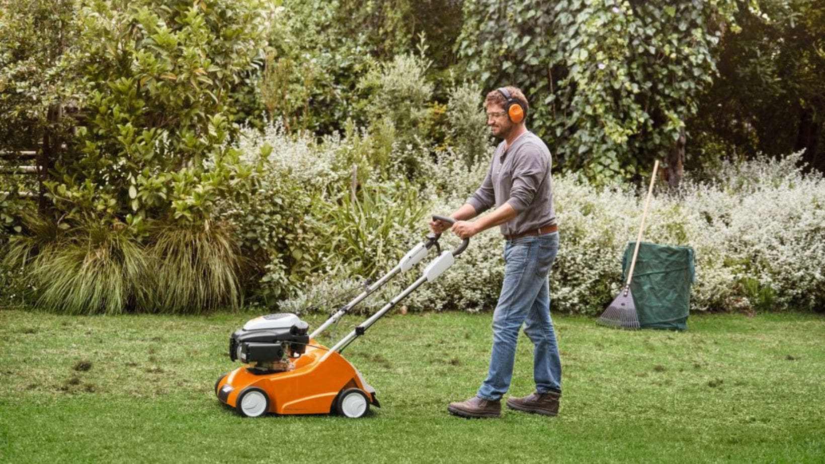 a man pushing a STIHL RL 540 Petrol Lawn Scarifier along a lawn