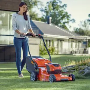 a woman mowing her lawn to prepare her garden for winter