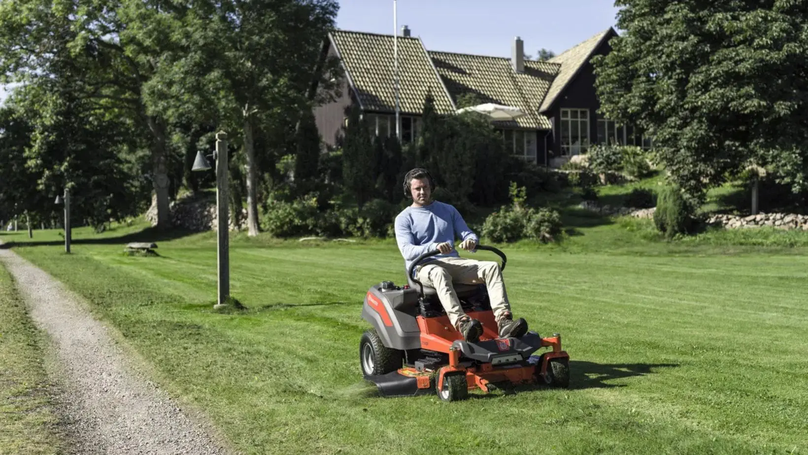 Husqvarna zero turn ride on mower-min a man using a ride on mower in a large garden