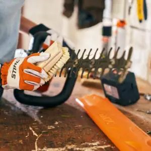 a man brushing debris off a hedge trimmer