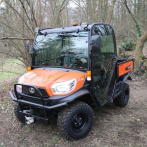 an orange Kubota RTV-X1110 Utility Vehicle parked in the clearing of a wood