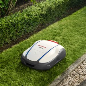 a white Honda Miimo robot mower mowing a narrow stretch of lawn