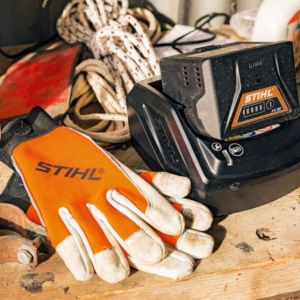 garden machinery batteries, a charger, and pair of orange and white STIHL protective gloves