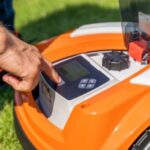 someone switching off an orange and white STIHL robot mower
