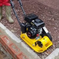 a close up of someone using a Handy THLC29140 Petrol Plate Compactor