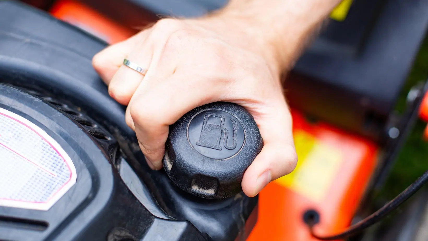 someone opening a lawnmower's fuel tank to check for stale fuel
