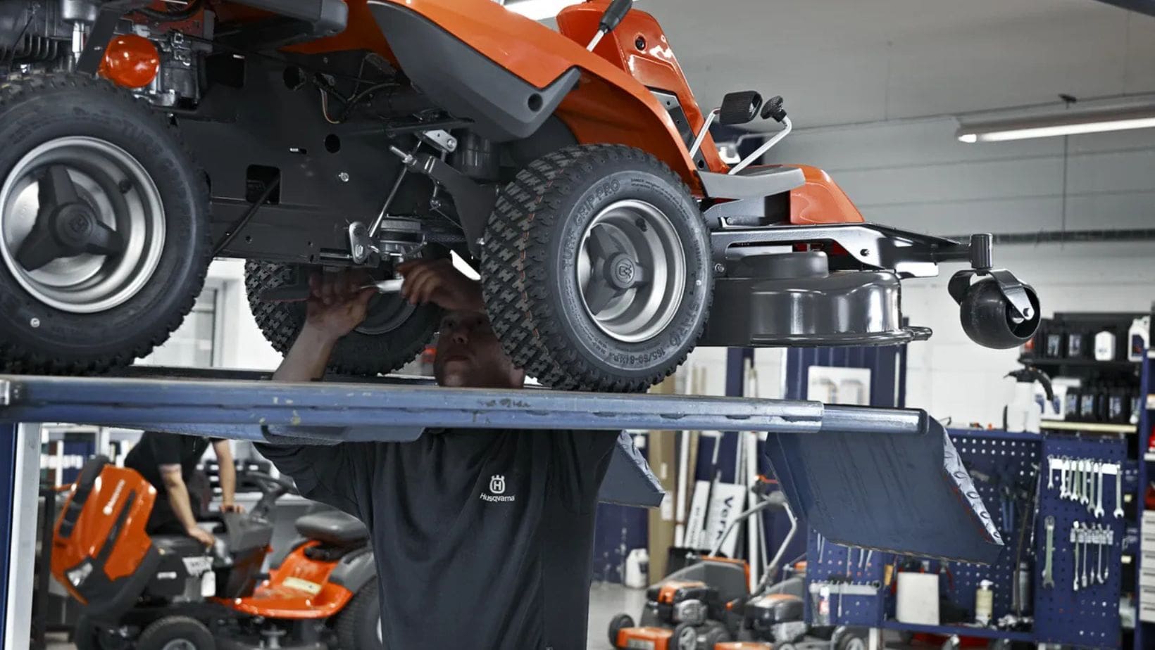 a man servicing the underside of a robotic mower in a workshop