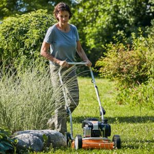 a professional gardener mowing a lawn, surrounded by trees and shrubs