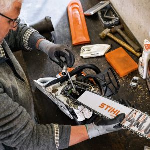 a man removing a chainsaw's bar as part of his garden machinery servicing