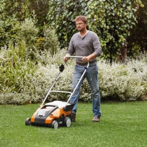 a man using a scarifier to remove thatch from a lawn