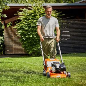 a man mowing a lawn with an orange STIHL lawnmower