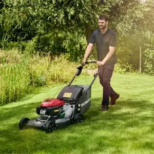 a man mowing a lawn with a Honda lawnmower