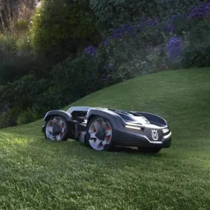 a black Husqvarna Automower travelling over undulating ground