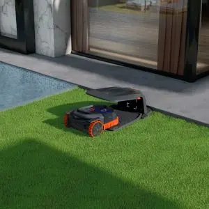 a Segway Navimow going into its charging station on a lawn, next to a house
