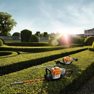 2 STIHL hedge trimmers sat on top of one of a number of ornamental hedges in a large garden