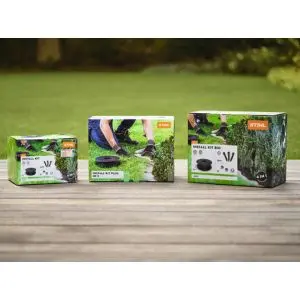 3 boxed STIHL iMow robotic mower installation kits, on a wooden table, in a garden