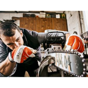 a man wearing STIHL gloves, using a file to sharpen a chainsaw chain