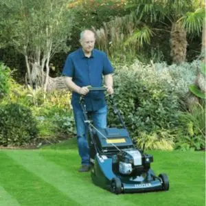 a man in a garden, mowing a lawn using the Hayter Harrier 56 BBC VS Petrol Lawnmower