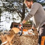 a man with a beard, wearing gloves and safety glasses, cutting firewood with a STIHL MSA 70 Cordless Chainsaw