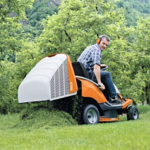 a man sat on the STIHL RT 4082 Petrol Ride-on Lawn Mower, using the controls to automatically empty the grass collector