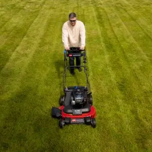 an overhead shot of a man wearing sunglasses, pushing the Toro Timemaster TM76K