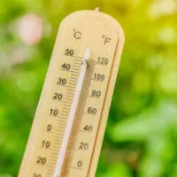 a close up of a thermometer showing a hot temperature in a garden