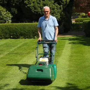 a man using the Allett Kensington 17B Cylinder Lawnmower to create lawn stripes