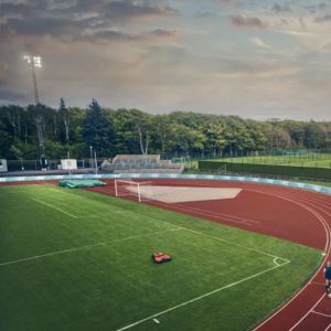 an ariel shot of a robot mower mowing a football pitch, which is surrounded by an athletics track