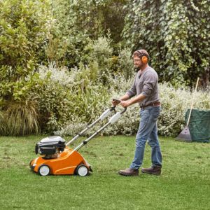 a man wearing ear defenders using the STIHL RL 540 Petrol Lawn Scarifier to scarify a lawn