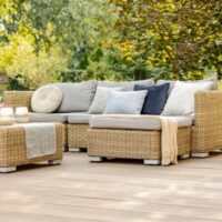 a rattan garden furniture set with cushions, positioned on wooden decking