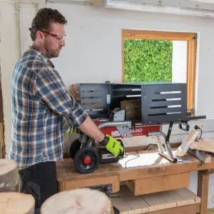a view from behind a man operating the AL-KO Easy LSH 3704 Electric Log Splitter, inside a workshop