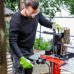 a man wearing safety glasses, plugging the AL-KO Easy LSV 5506 Electric Log Splitter into a power socket