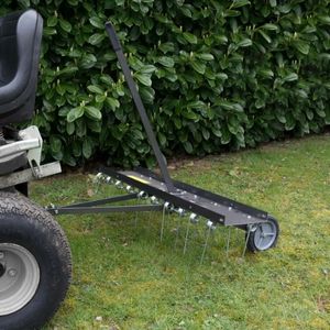 close up of the Handy THTD Dethatcher being towed across a lawn by a ride-on mower