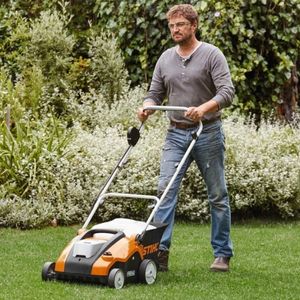 a man pushing the STIHL RLA 240 Cordless Lawn Scarifier across a lawn