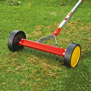the Wolf-Garten Multi-Change Roller Moss Removal Rake taking away surface thatch from a lawn