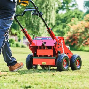 a shot taken from behind a man pushing the Camon LA25 Lawn Aerator across a lawn, which show the aerator's metal tines