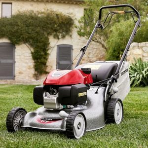 the Honda HRG466 013 RGB Mower on a lawn, outside a large house
