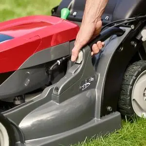 a close-up of someone adjusting the cutting height on a Honda HRX lawnmower