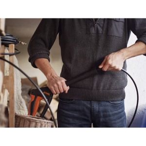 a man connecting a drainpipe cleaning attachment to a pressure washer