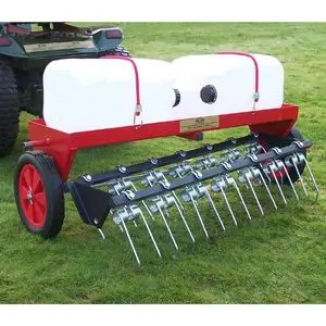 a riding mower towing the SCH DTC 40-Inch Dethatcher attachment across a lawn