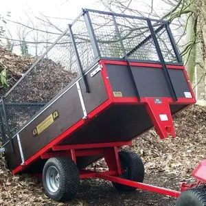 the SCH GWTS15 Trailer, attached to a riding mower, tipping its load against a bank