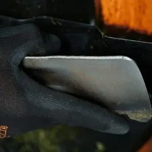 someone wearing a black glove, holding a lawnmower blade