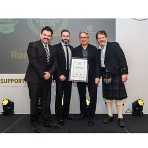 four smartly dressed men, one of whom is holding an award