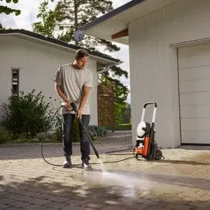 a man using the Husqvarna PW 240 Pressure Washer to jet wash a driveway