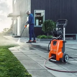 a man pressure washing a patio outside a house, using a Husqvarna jet wash