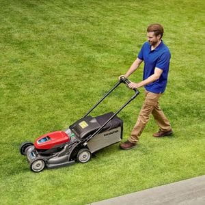 a man wearing a blue polo shirt, mowing a lawn with the Honda HRX 476 XB Cordless Lawn Mower