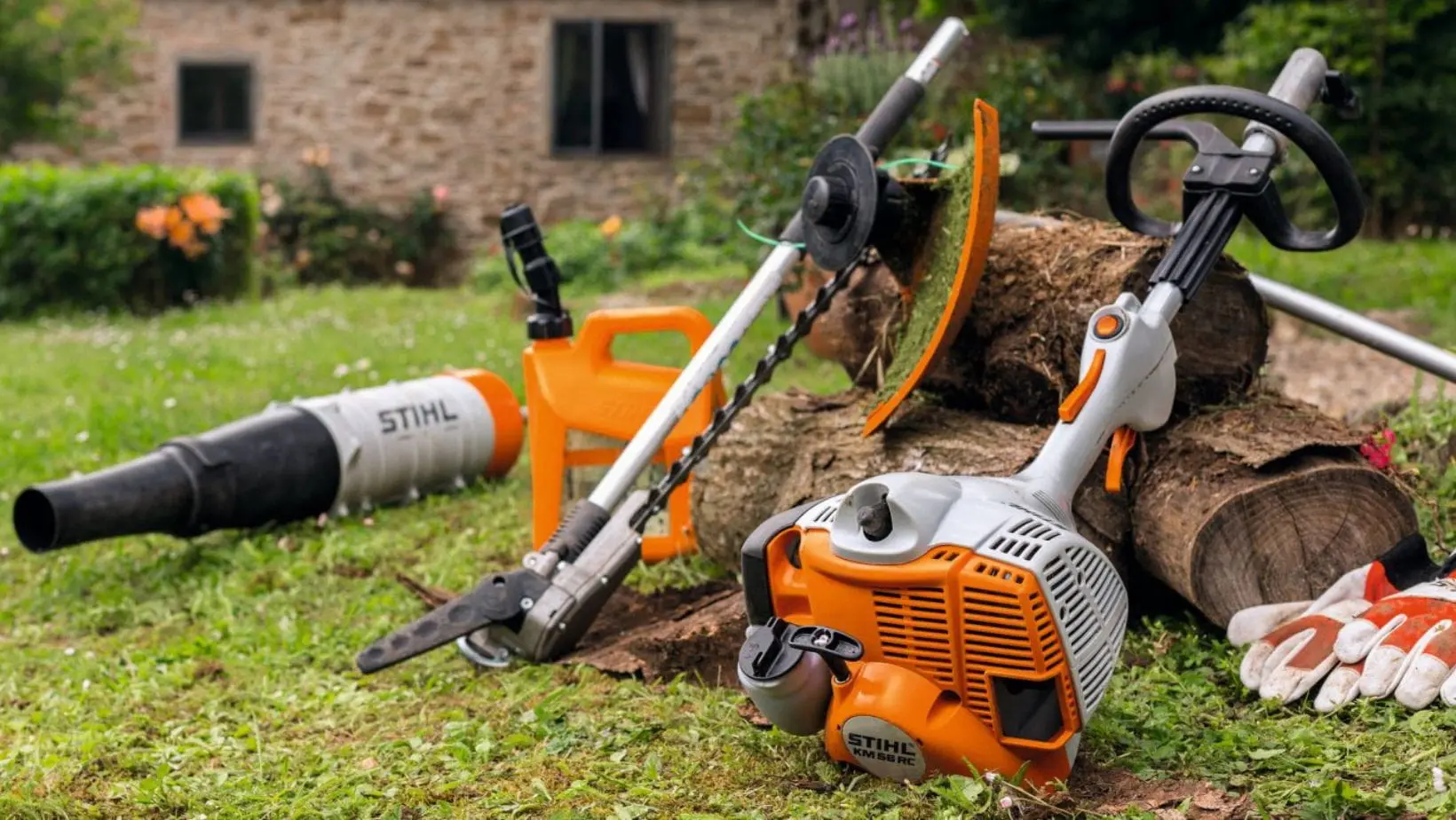 the STIHL KM 56 RC-E Petrol KombiEngine plus several multi tool attachments and a fuel can, resting against or near a small pile of logs in a garden