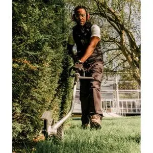 a man operating the Honda UMC 435 E Versatool with edger attachment, where a lawn meets a hedge