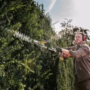 a man trimming a hedge with the Honda UMC 435 E Versatool 15 multi tool